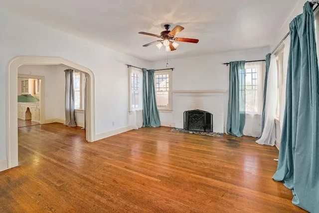 a view of an empty room with wooden floor fireplace and a window