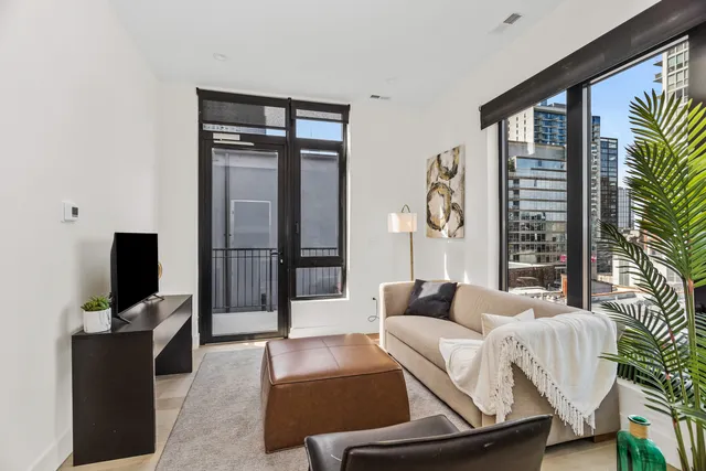 a living room with furniture a floor to ceiling window and flat screen tv