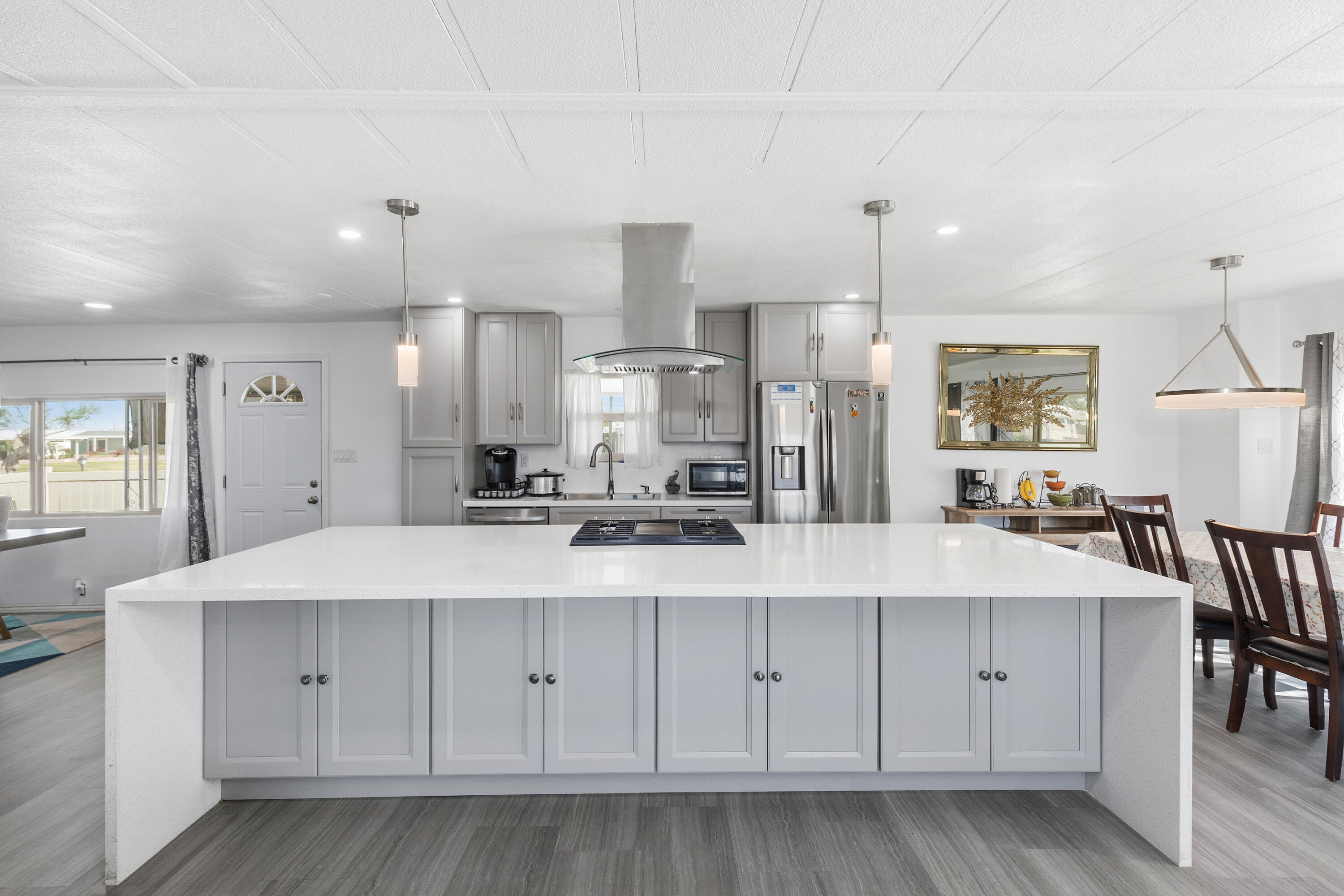 a large white kitchen with wooden floors stainless steel appliances and cabinets