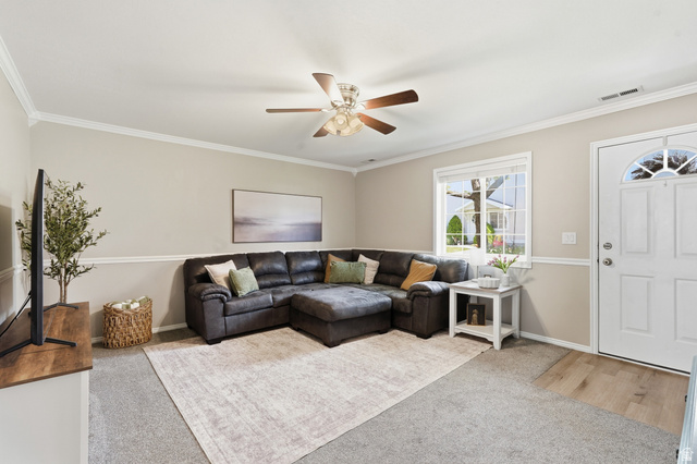 99 Penhurst Place Logan, UT 84341 - Photo 5 of 34 Living room featuring crown molding, two-tone wall treatment, a ceiling fan with light fixture, a window with exterior views, and a front entry door with an arched glass insert
