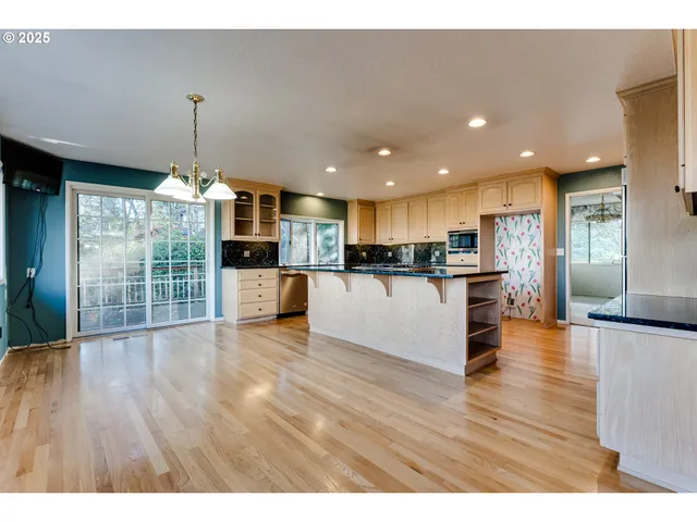 a kitchen with stainless steel appliances wooden floor and view living room