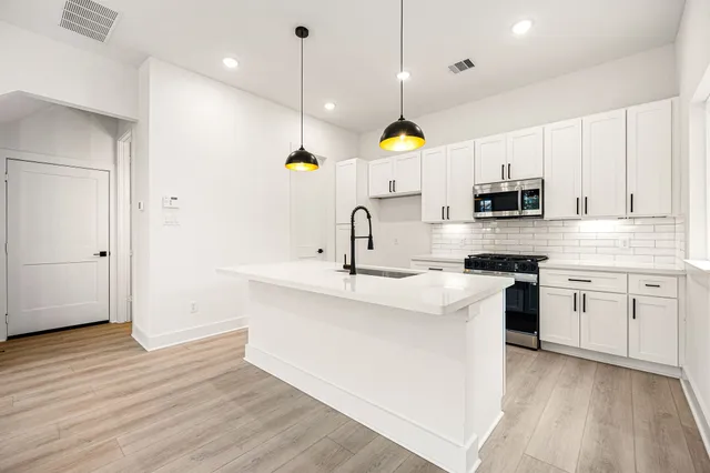 a kitchen with kitchen island granite countertop a sink a stove and wooden floors