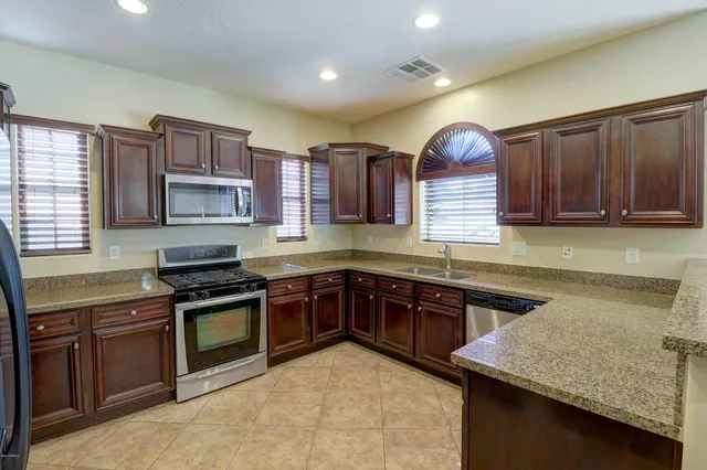 a kitchen with stainless steel appliances granite countertop wooden cabinets a stove top oven a sink and dishwasher