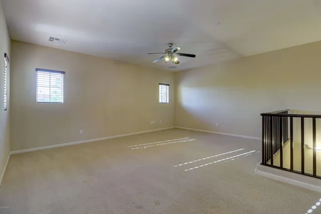 en empty room with windows and ceiling fan