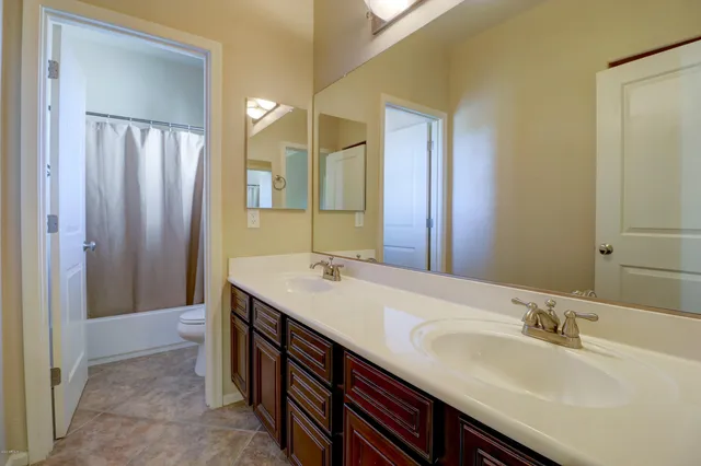 a bathroom with a double vanity sink a large mirror and a shower