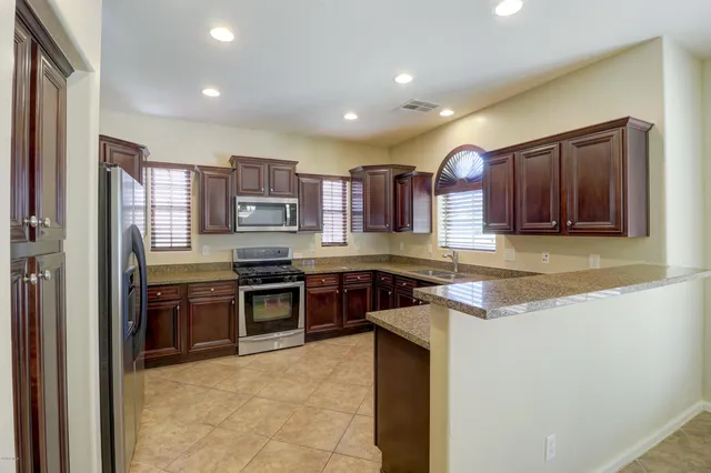 a kitchen with stainless steel appliances granite countertop wooden cabinets a stove a sink and a refrigerator