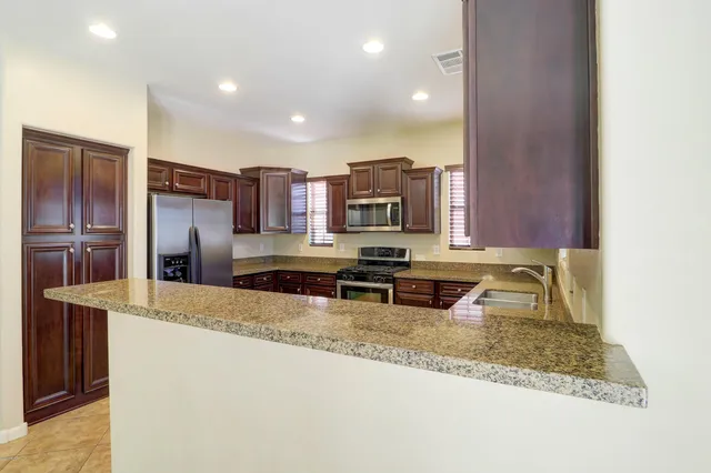 a kitchen with stainless steel appliances granite countertop a sink refrigerator and cabinets