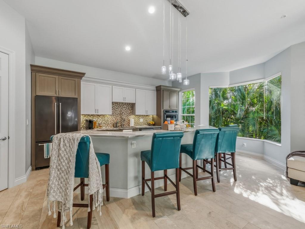 175 Colonade Circle Naples, FL 34103 - Photo 8 of 45 a kitchen with a table chairs refrigerator and cabinets