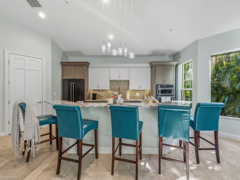 175 Colonade Circle Naples, FL 34103 - Photo 9 of 45 a kitchen with a dining table chairs and refrigerator