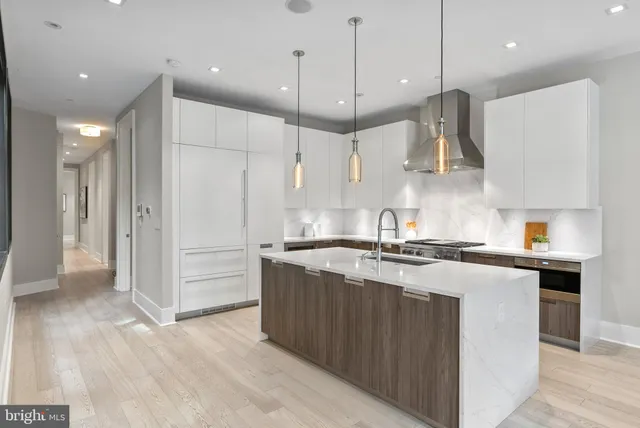 a kitchen with stainless steel appliances granite countertop a stove a sink a refrigerator and a oven with wooden floor