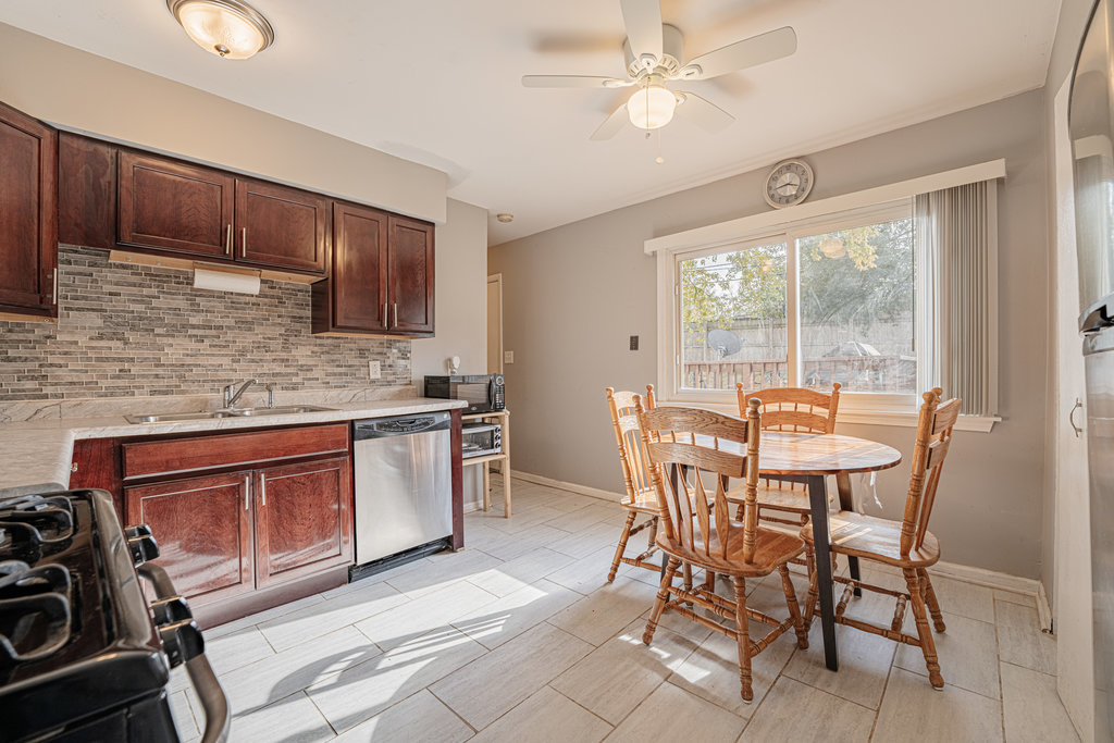 213 Rockhurst Road Bolingbrook, IL 60440 - Photo 5 of 14 a kitchen with stainless steel appliances granite countertop a stove top oven a sink dishwasher a dining table and chairs with wooden floor