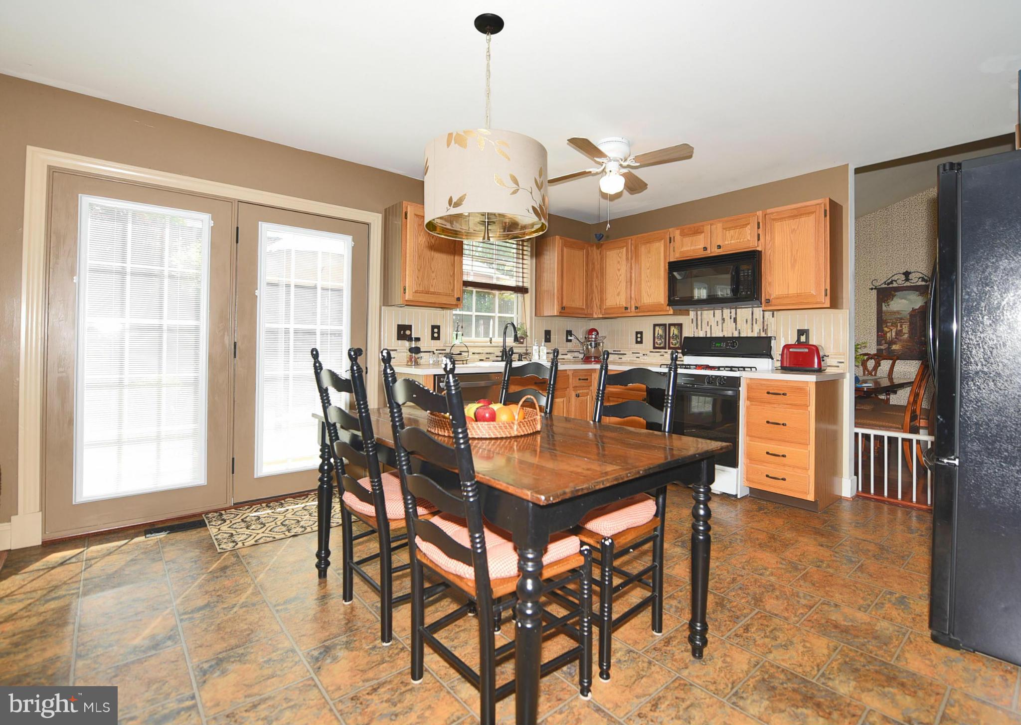 4505 King George Court Nottingham, MD 21236 - Photo 10 of 30 a dining room with stainless steel appliances kitchen island granite countertop a table chairs and a refrigerator