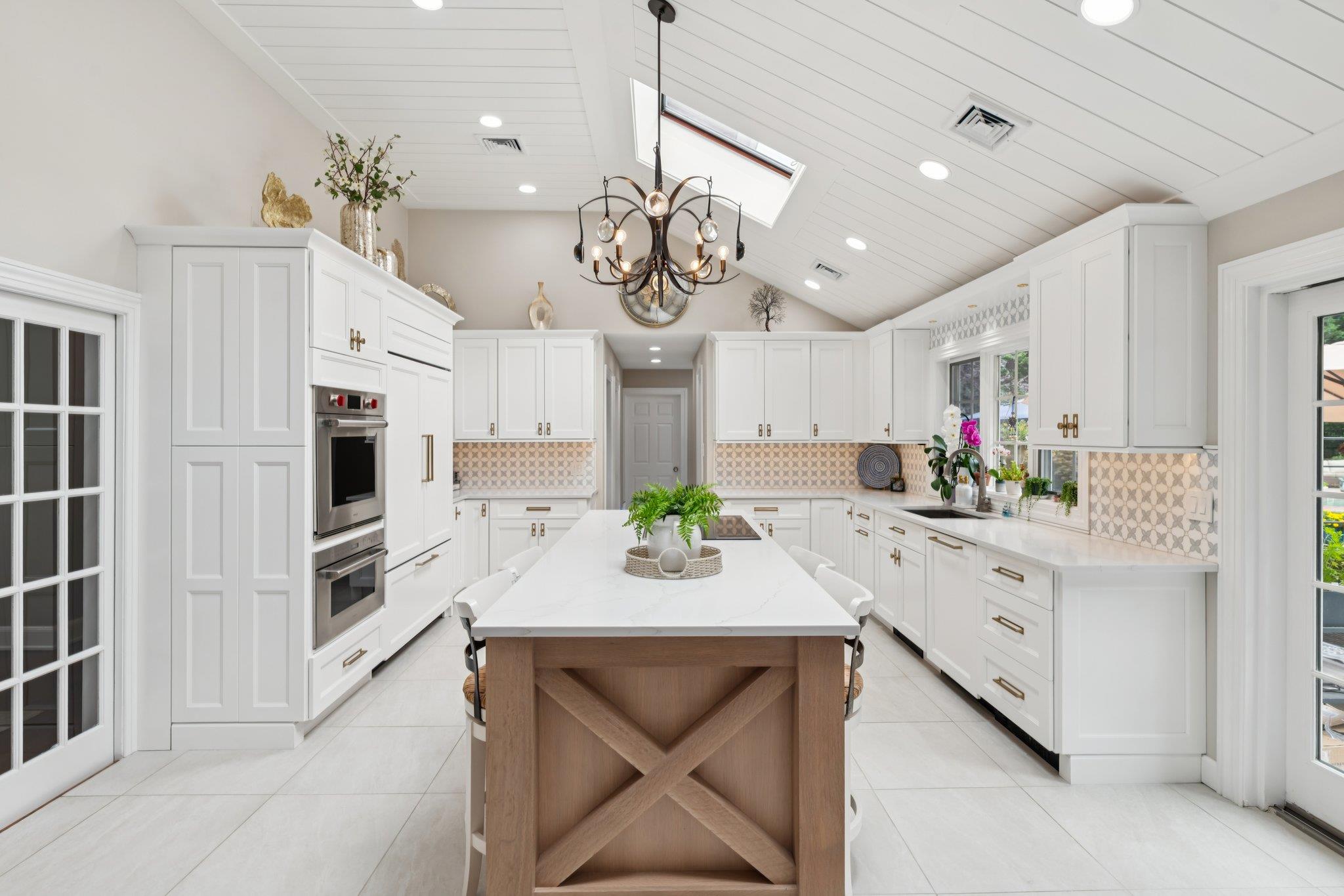 21 Inlet View Path East Moriches, NY 11940 - Photo 10 of 40 Kitchen featuring a skylight, white cabinets, a chandelier, tasteful backsplash, and light tile patterned flooring