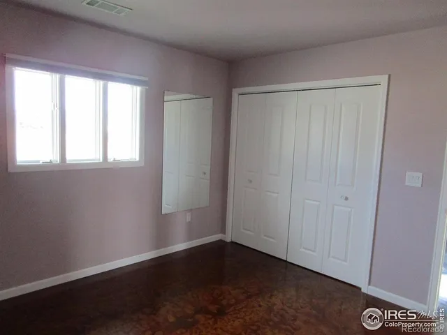 an empty room with wooden floor and windows with curtains