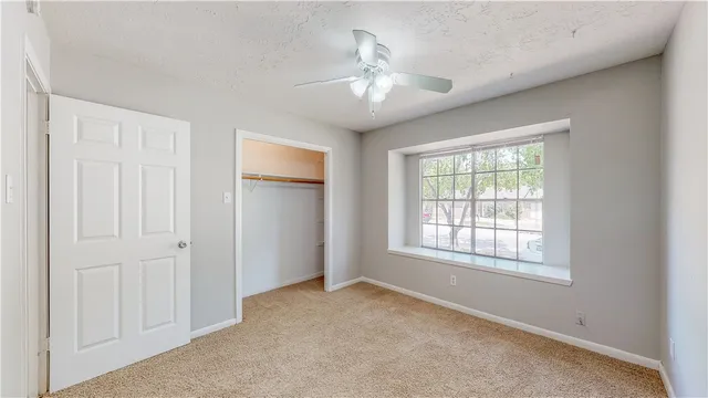 an empty room with chandelier fan and windows