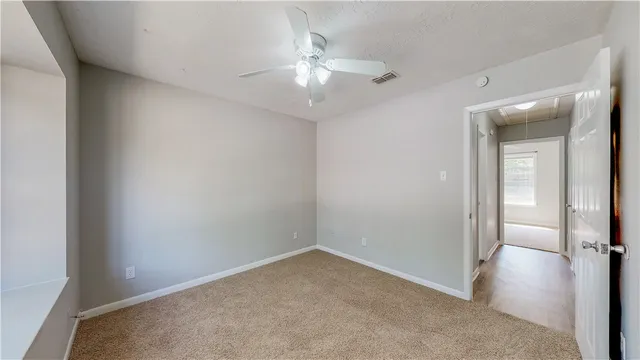 an empty room with a chandelier fan and glass door