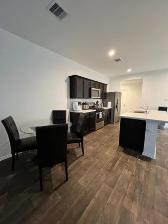 a living room with stainless steel appliances kitchen island granite countertop a table chairs microwave and sink