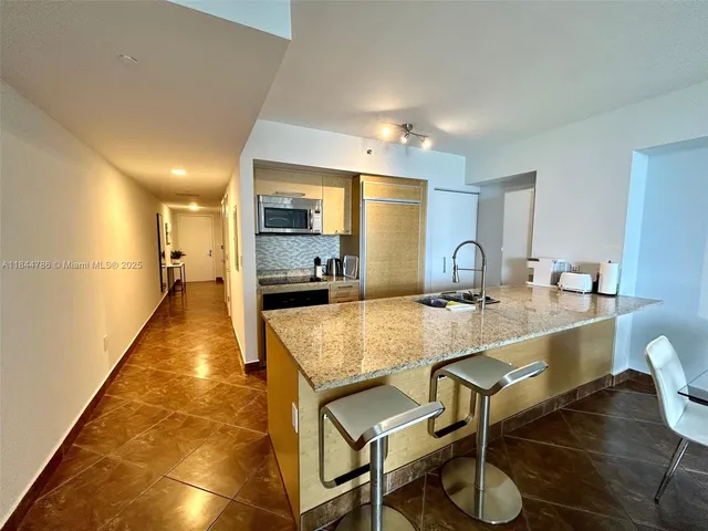 a large dining hall with stainless steel appliances granite countertop a sink and a counter top space
