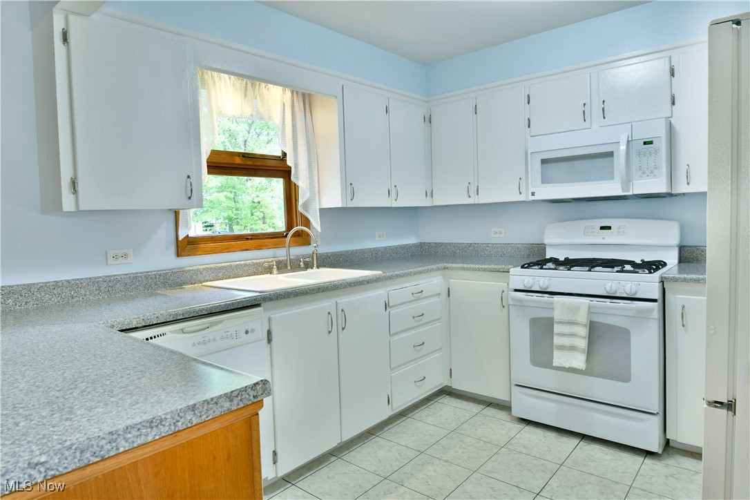 6509 Shaffer Road Northwest Warren, OH 44481 - Photo 22 of 50 Kitchen featuring white appliances, a sink, light tile patterned floors, light countertops, and white cabinets