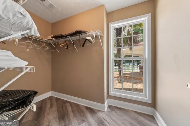 a bedroom with a bed a dresser and potted plants with wooden floor