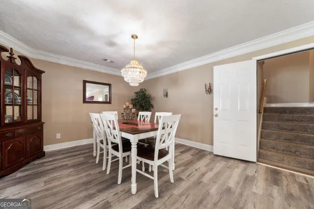 a kitchen with stainless steel appliances kitchen island granite countertop a stove a refrigerator a sink a dining table and chairs with wooden floor