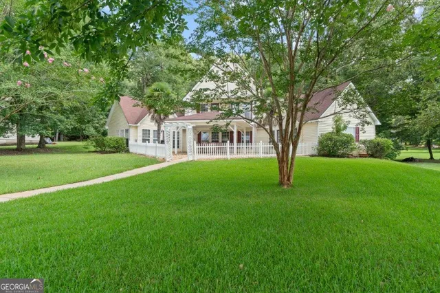 a view of house with a big yard and large trees