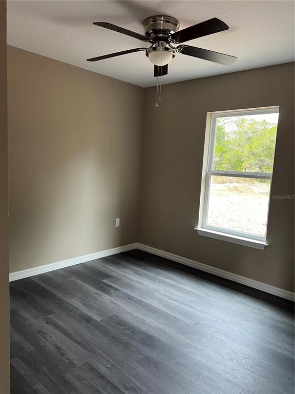 20855 Beach Boulevard Dunnellon, FL 34431 - Photo 12 of 14 an empty room with wooden floor fan and windows