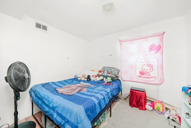 a bedroom with a bed a wall painting and a lamp