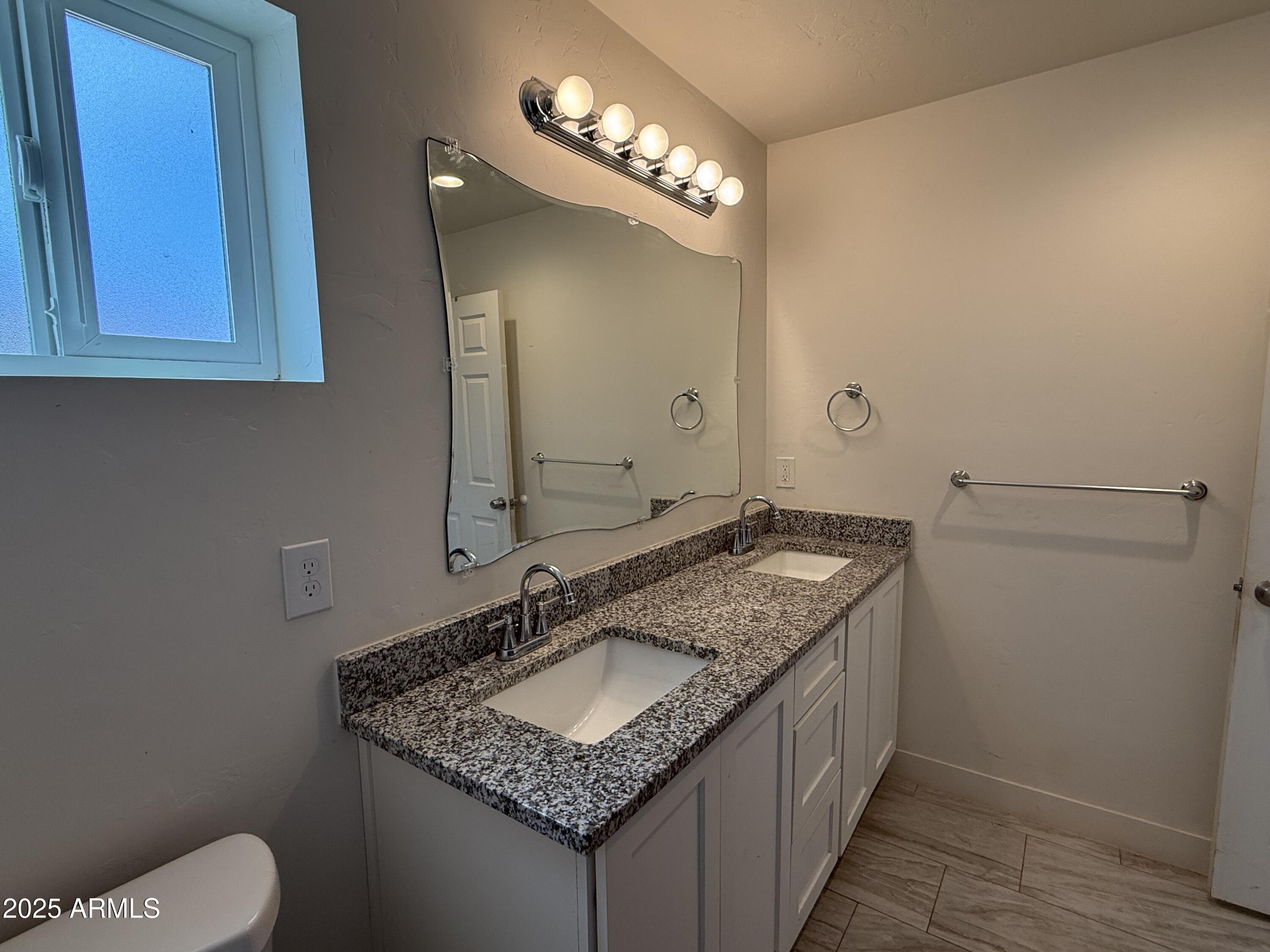 286 Guaymas Court Rio Rico, AZ 85648 - Photo 11 of 16 a bathroom with a granite countertop sink a toilet and a mirror