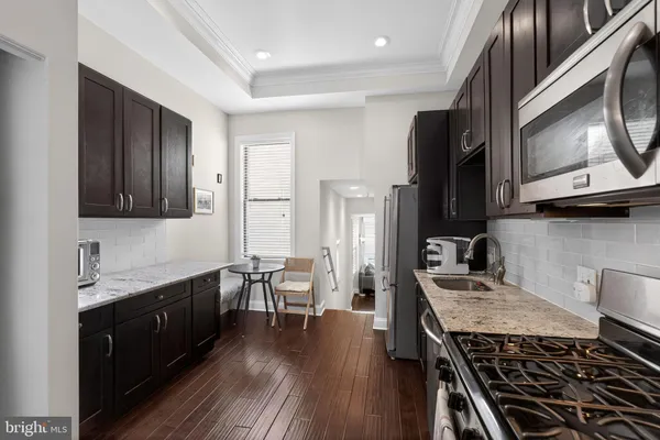 a kitchen with stainless steel appliances granite countertop a stove and a wooden floors