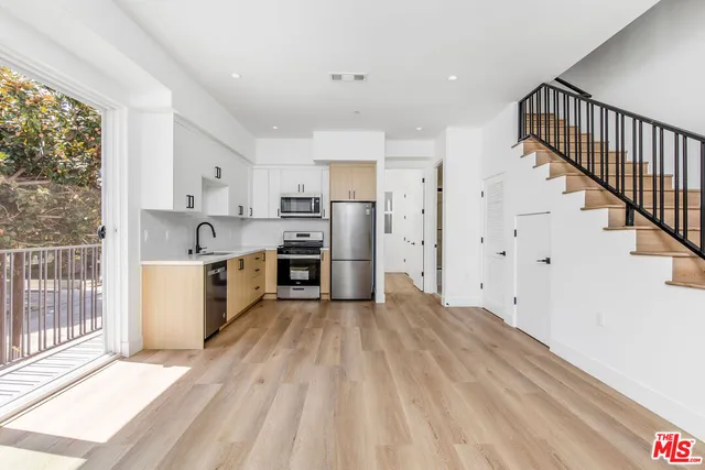 a view of a kitchen with a sink stove wooden cabinets and entryway