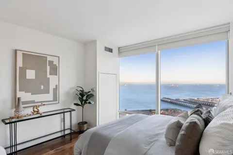 a bedroom with a balcony a bed and a large window