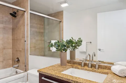 a bathroom with a granite countertop sink a mirror and a bathtub