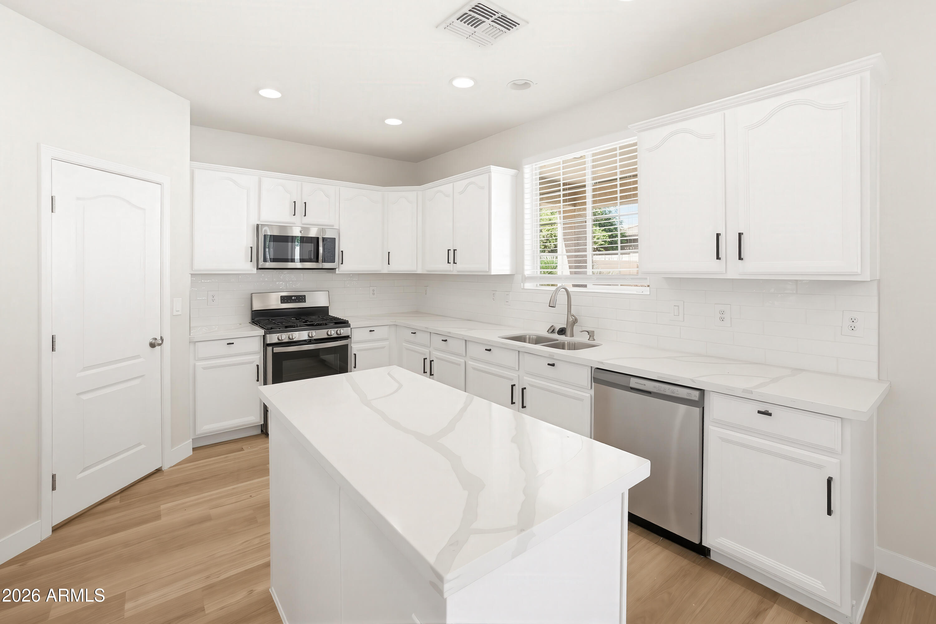 17328 West Bajada Road Surprise, AZ 85387 - Photo 5 of 40 a kitchen with kitchen island white cabinets and white appliances