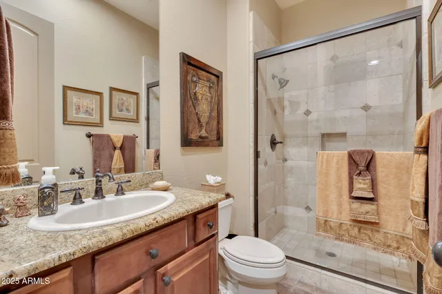 a bathroom with a granite countertop sink a mirror a toilet and shower