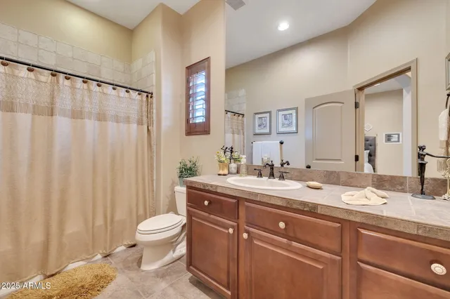 a spacious bathroom with a granite countertop sink a toilet and a mirror