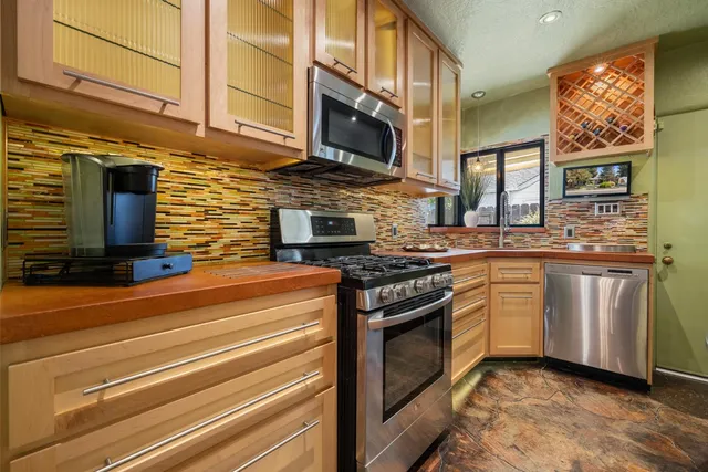 a kitchen with stainless steel appliances granite countertop a stove a sink and a microwave
