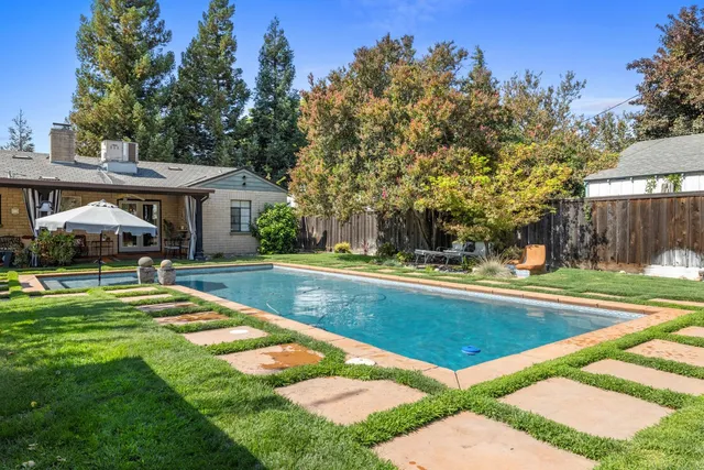 a view of swimming pool with lawn chairs and plants