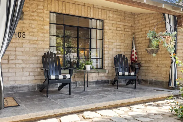 a view of a brick house with chairs in patio