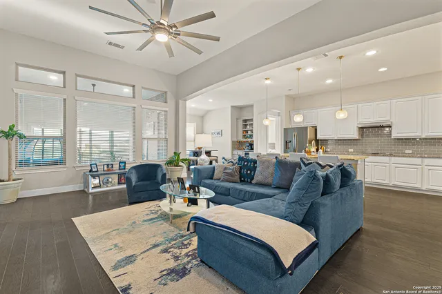 a living room with furniture kitchen view and a large window