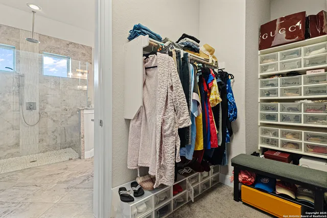 a view of walk in closet with clothes and shoes