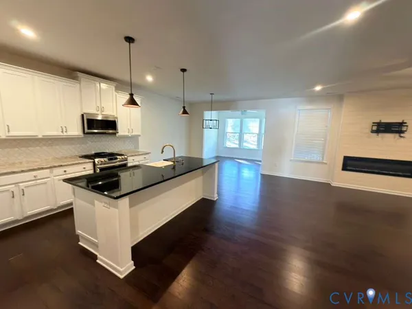 a kitchen with granite countertop a stove and a wooden floor