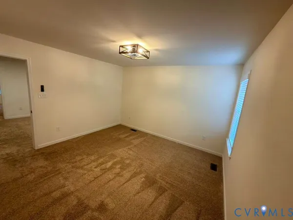 en empty room with chandelier fan and kitchen view