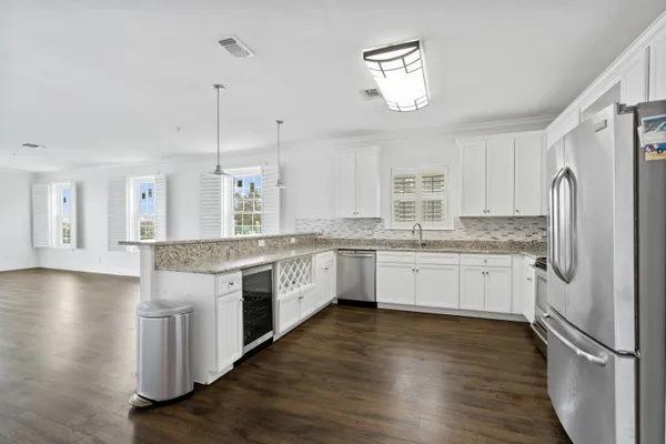 a large kitchen with granite countertop a large counter top a sink stainless steel appliances and cabinets