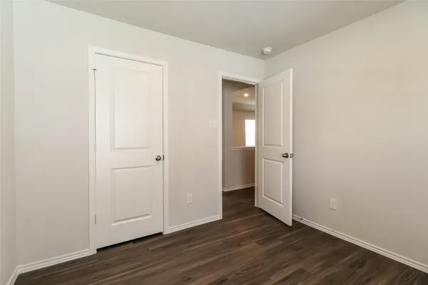 an empty room with wooden floor & closet area
