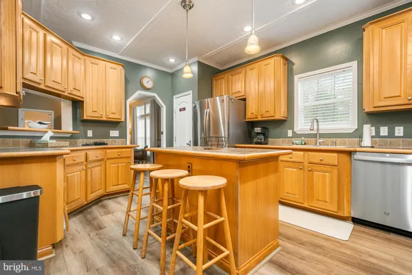 a large kitchen with cabinets a sink a center island and stainless steel appliances