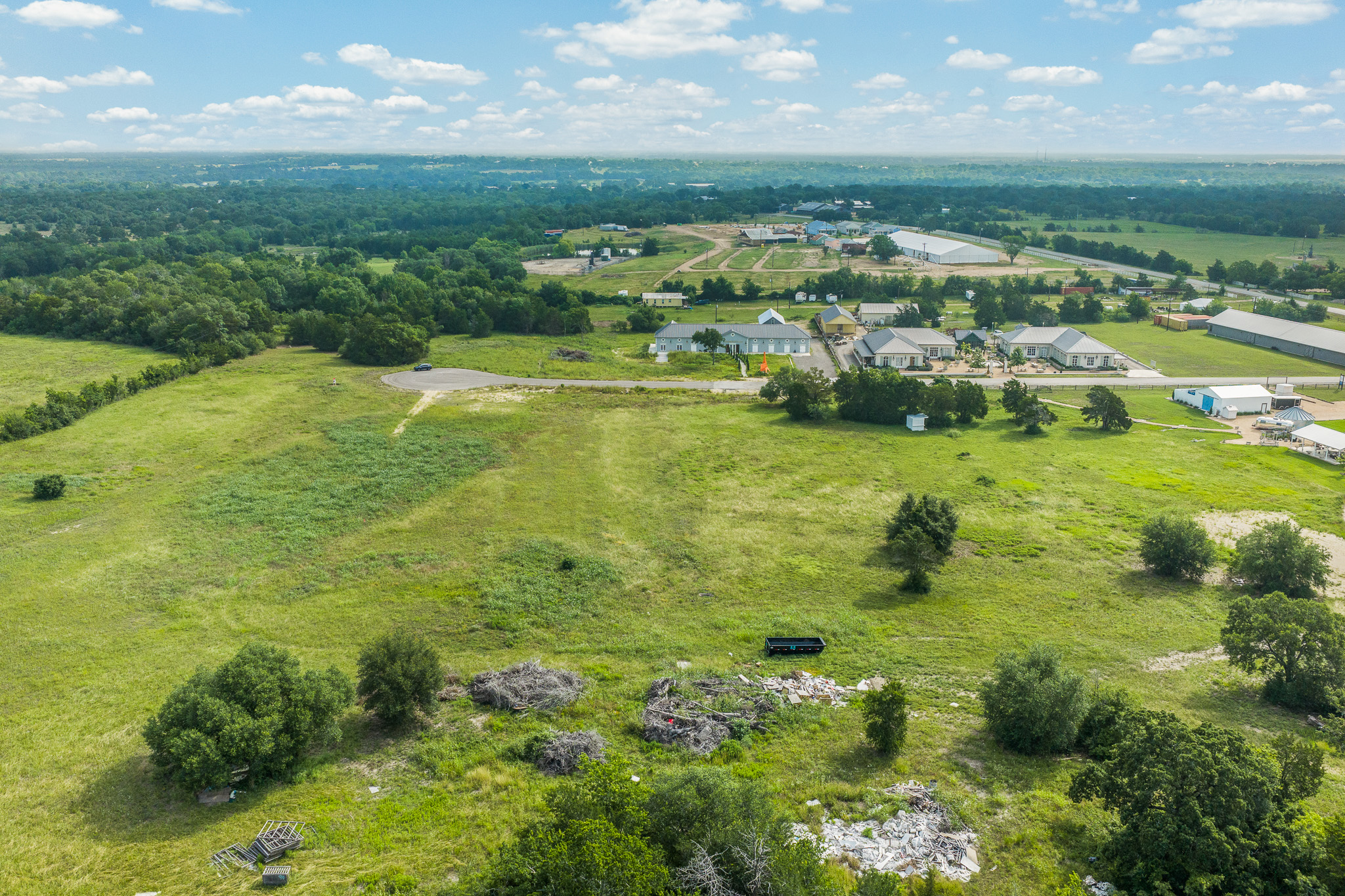 109 Compound Lane Round Top, TX 78954 - Photo 14 of 23 A vast, verdant expanse with distant buildings under a boundless sky offers potential for development.