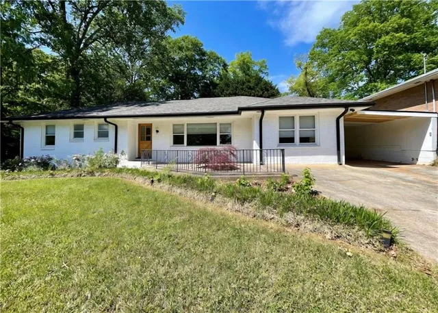 a front view of house with yard and trees in the background