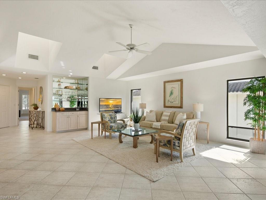 770 Eagle Creek Drive, Unit 301 Naples, FL 34113 - Photo 5 of 46 a living room with furniture and a dining table with projector the kitchen
