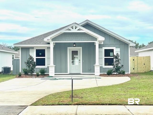 View of front of home with a front lawn, central air condition unit, and covered porch